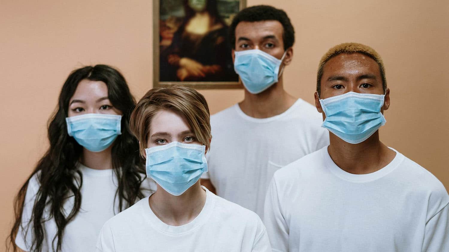 四位不同种族背景的青年站在一起戴掩鼻口罩