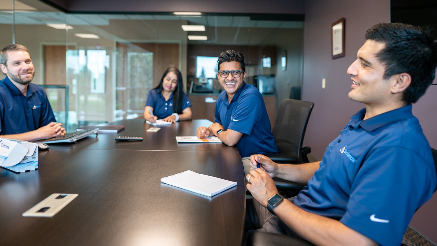 西英西克斯成员坐在会议桌旁聊天身穿蓝波罗和公司标识匹配